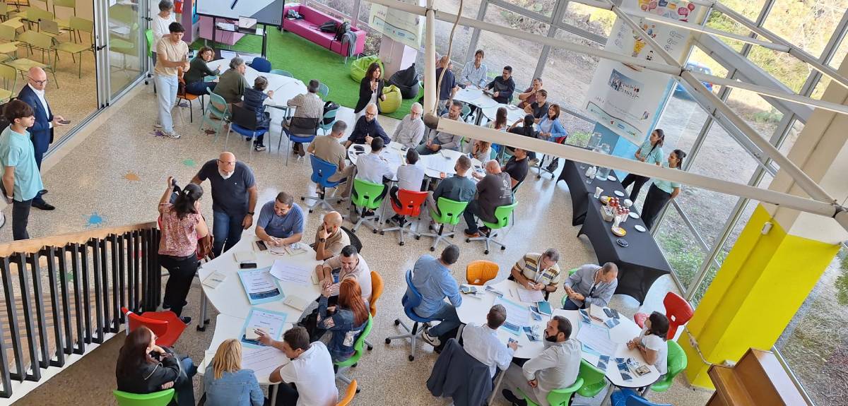 Cinco grupos de personas reunidas en torno a mesas, fotografiados desde un piso superior